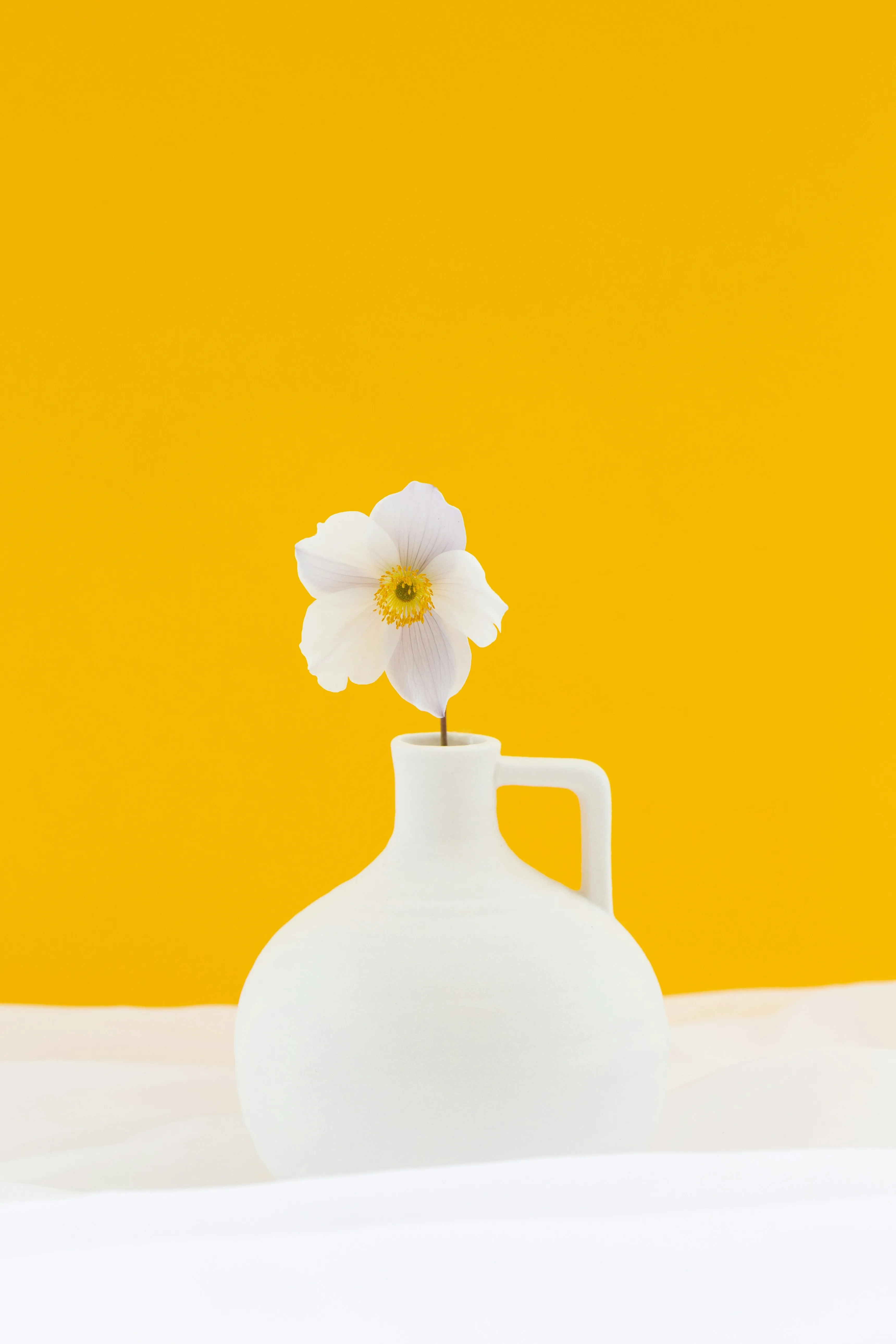 Weiße Blüten in schlichter Vase, Wasserschale als Mitte der Trauerfeier